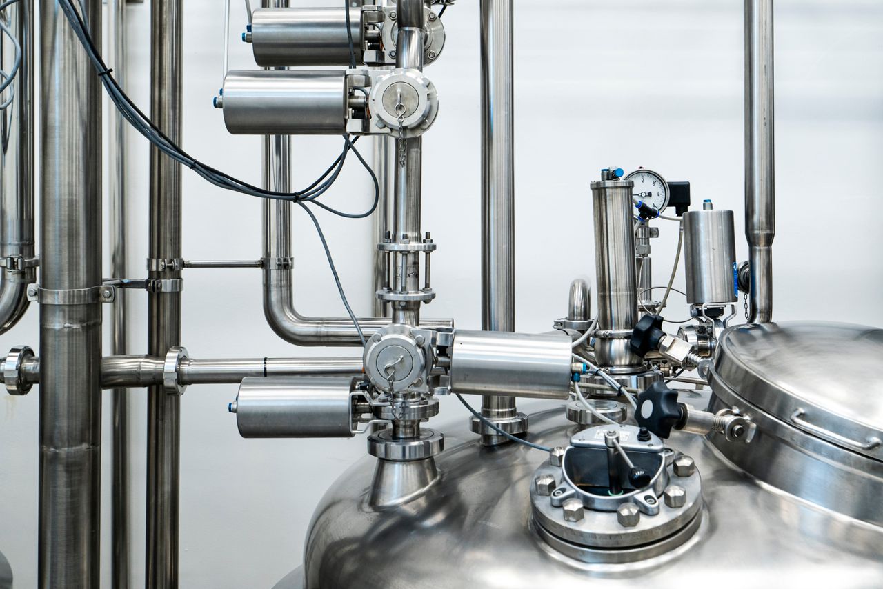 Close-up of stainless steel machinery and pipes in an industrial setting, showcasing modern engineering.